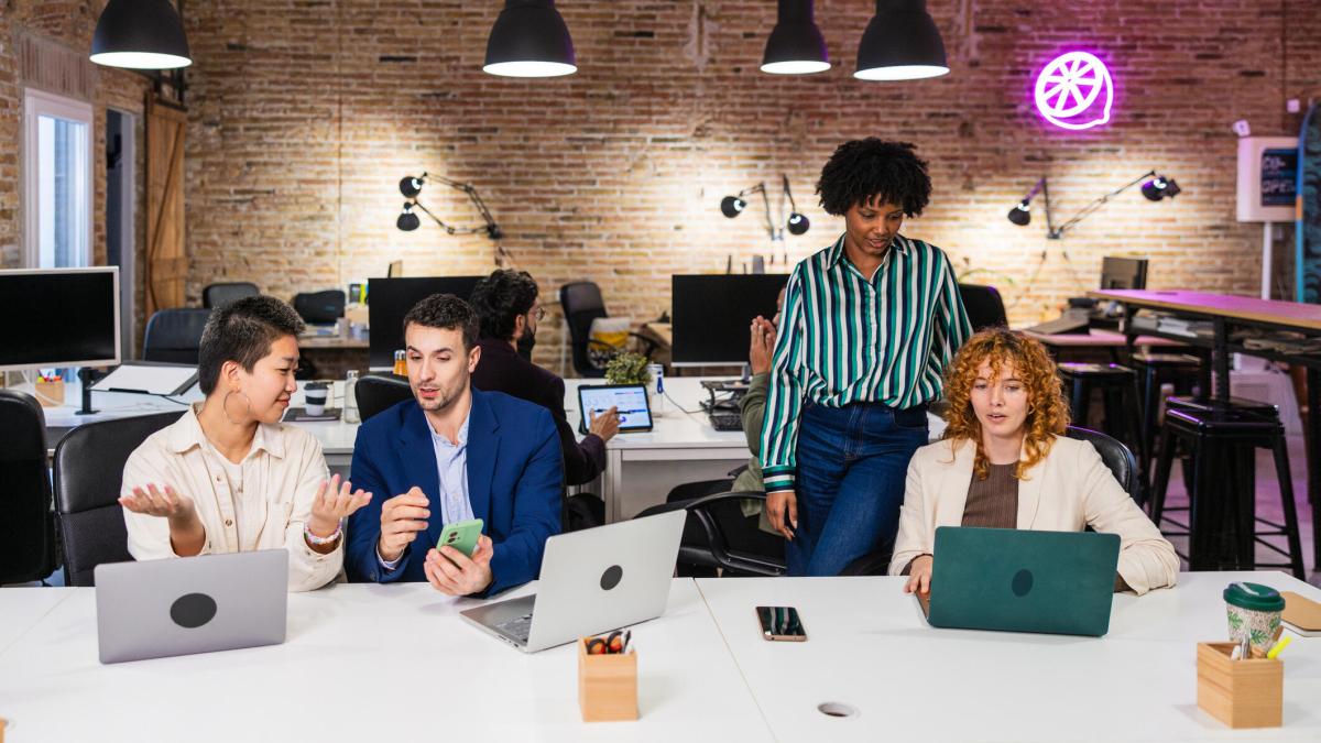 A photo of four people working in an office that's lit by a neon light