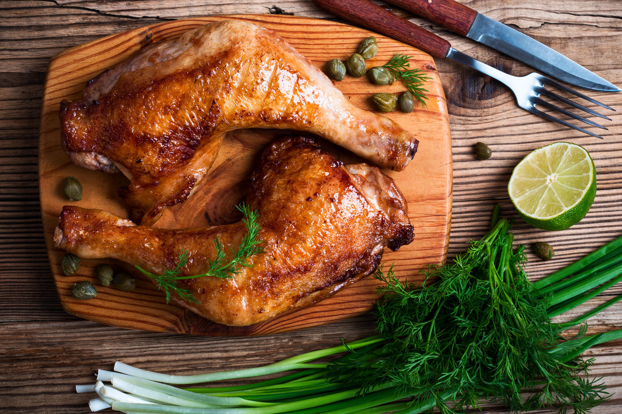 Cooked chicken thighs and green onions are presented on a serving platter.