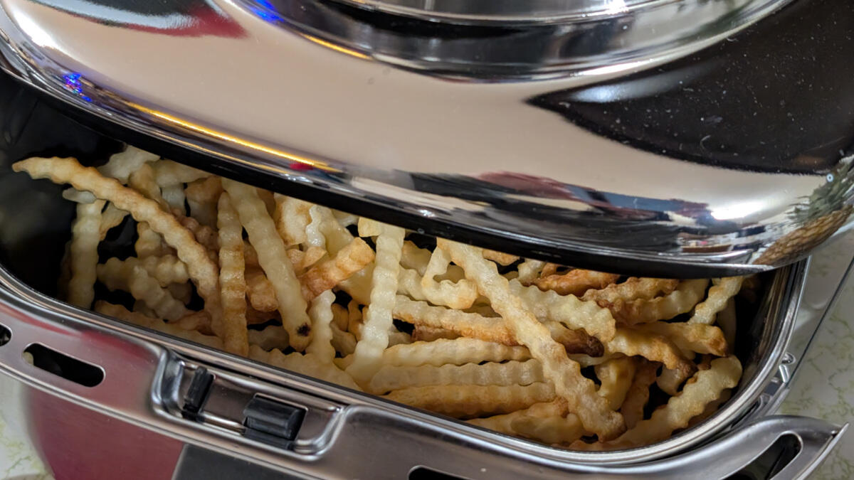 cosori-iconic-air-fryer-resting-on-white-countertop-with-basket-full-of-french-fries